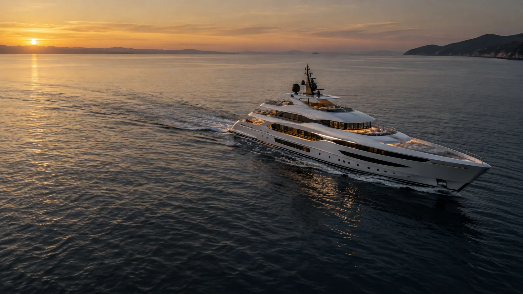An elegant private yacht crossing still Mediterranean water at sunset.